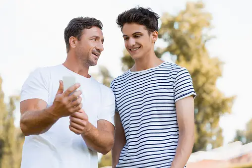 Father and son looking at phone What is OnlyFans and Why Is It So Dangerous