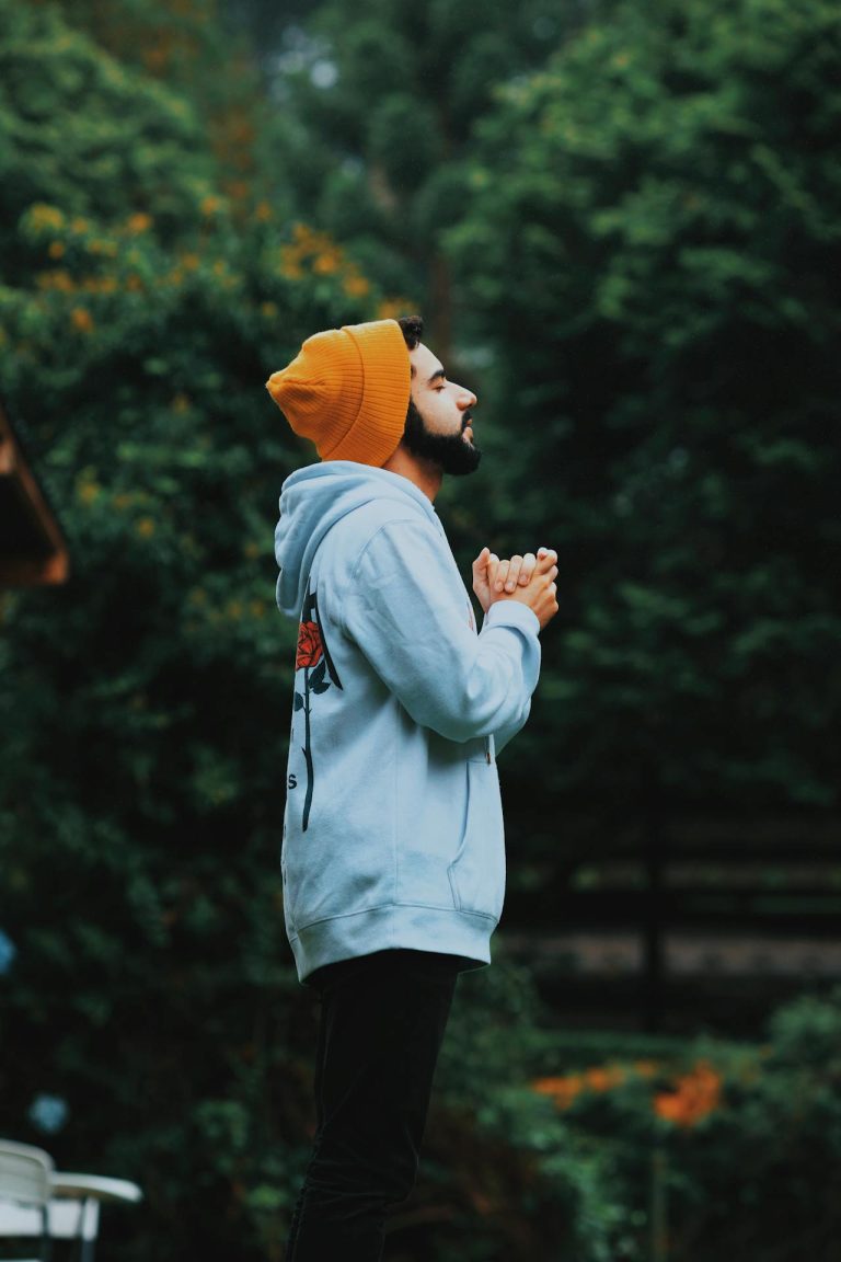 Young man in sweatshirt praying out in nature - benefits of quitting porn